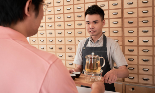 Employee with disability handing a tray of tea to a customer.