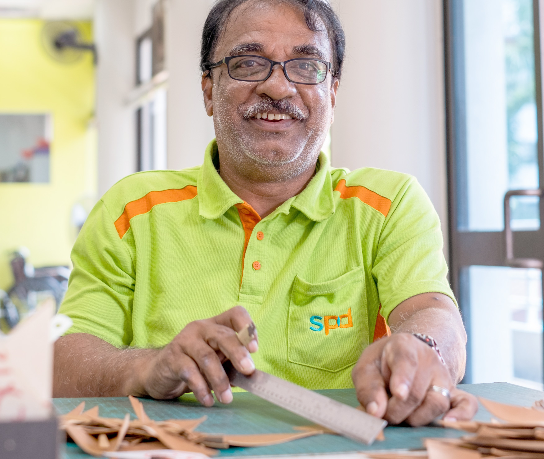 Mohamed Hussain from SPD joyfully smiles at the camera while assembling pieces of the journal