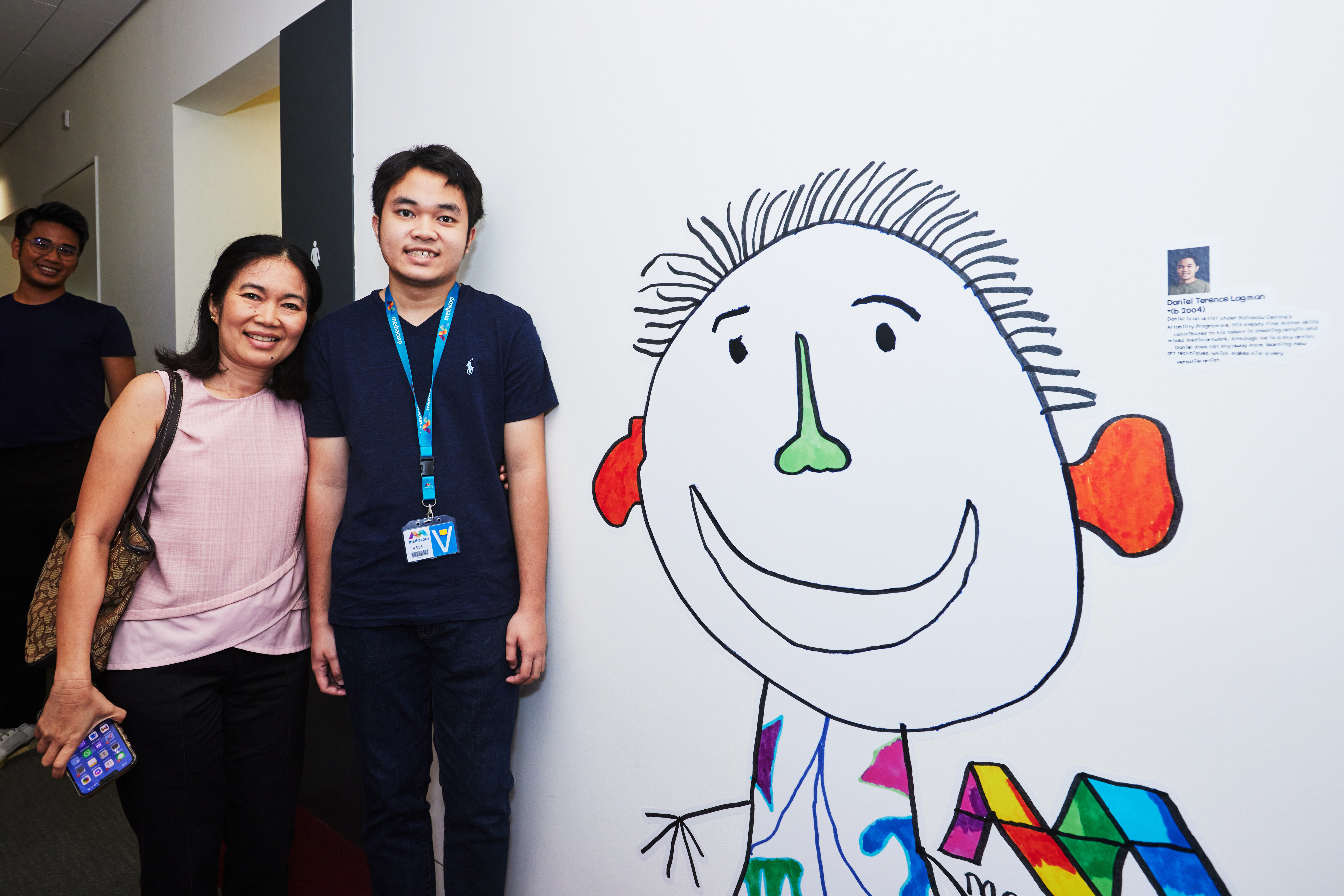 Daniel Terence Lagman  - Artist from Rainbow Centre, smiles brightly with his mother beside his wall sticker mural