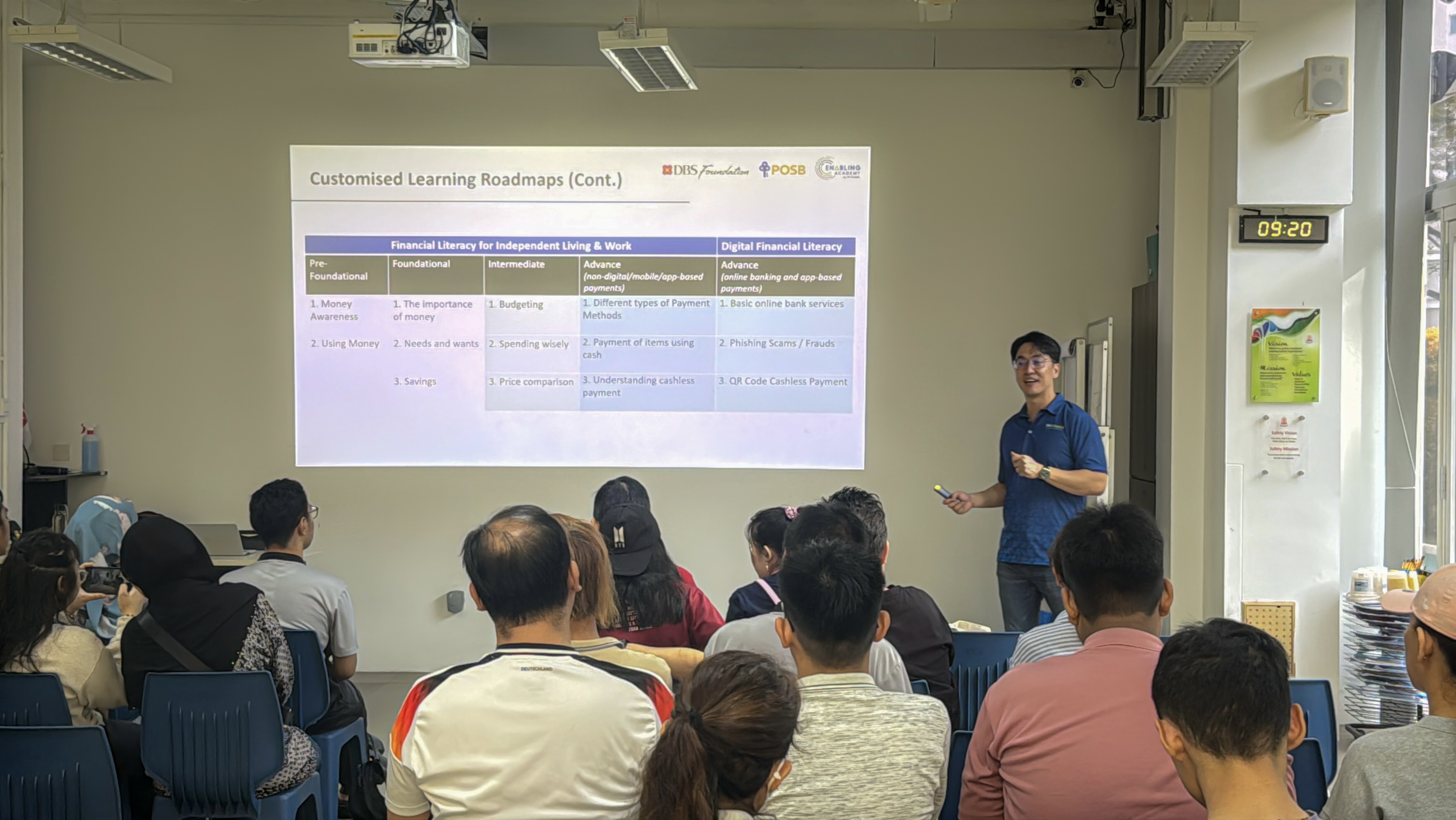 Representative from Enabling Academy in blue collared T-shirt delivering a presentation to a group of caregivers